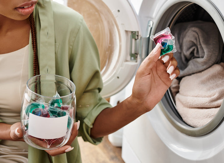 A woman putting a laundry scent booster into a washing machine